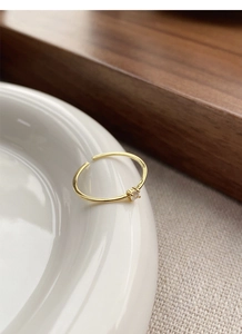 Detail of minimalist gold-plated adjustable ring with a sparkling clear cubic zirconia