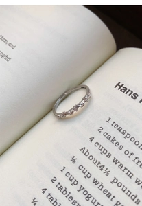 Macro shot of silver wheat leaf ring with zircon stones on an open book page