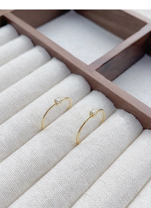 Close-up of two minimalist gold S925 silver rings with round four-prong set zircons