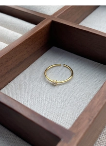 Macro detail of a minimalist gold S925 silver ring with a single cz stone in a wooden box