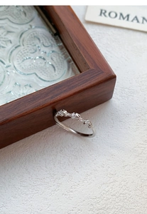 Detail of leaf-shaped silver ring with sparkling cubic zirconia on a wooden frame