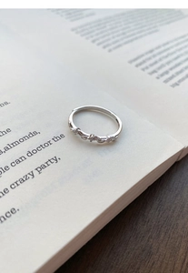 Close-up of adjustable silver wheat spike ring with zircon stones on a book