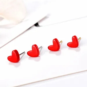 Vue macro de boucles d'oreilles cœur rouge brillant avec finition lisse sur fond blanc