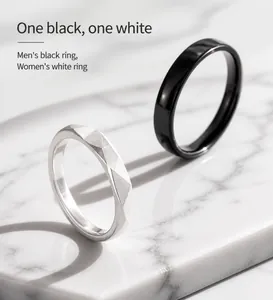 Vista detallada de anillos de pareja geométricos minimalistas en negro pulido y plata