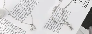 Detail of S925 sterling silver heart necklace and vintage rabbit pendant on a magazine