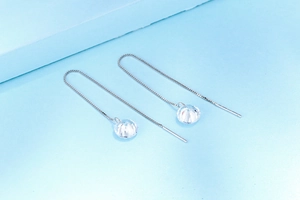 Detailed close-up of a long silver threader earring featuring a sparkling zircon pendant