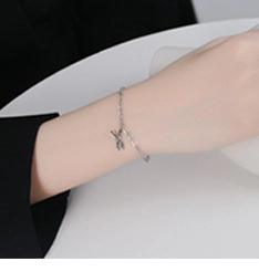 Detailed close-up of a minimalist silver rabbit charm on a delicate chain bracelet