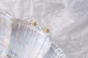 Macro shot of S925 sterling silver daisy earrings with textured petals and golden core
