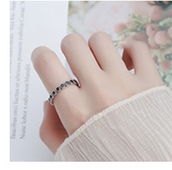 Macro shot of 925 silver ring with black square stones on a finger over a book