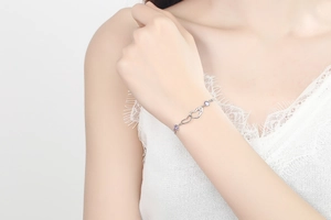 Detail of S925 sterling silver double heart bracelet with purple gemstones on woman wrist
