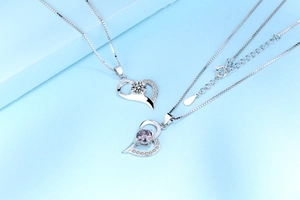 Detail of silver heart pendants featuring clear and lavender zircons on box chains