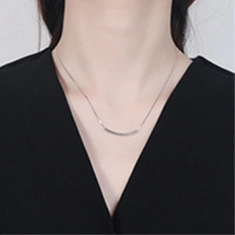 Detail view of a silver minimalist curved bar necklace worn on a neck with black collar