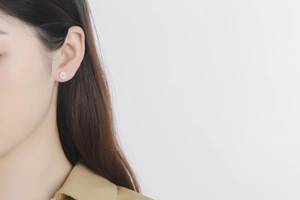 Close-up of a model wearing a small S925 silver daisy stud earring with yellow center