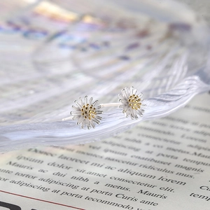 S925 sterling silver daisy stud earrings with golden pistils on a glass tray