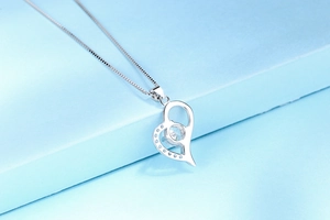Close-up of S925 sterling silver heart pendant with sparkling cubic zirconia on blue background