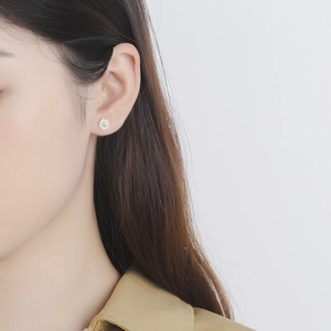 S925 sterling silver daisy stud earrings with gold center shown on a model's ear