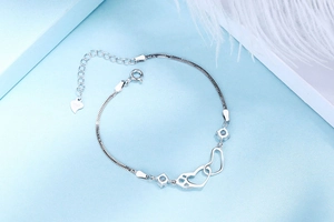 Detail of S925 sterling silver double heart bracelet with blue stones on a blue background