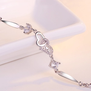 Macro detail of S925 silver interlocking double heart bracelet with I U engraving
