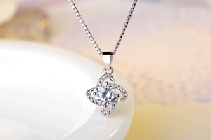 Macro shot of a silver four-leaf clover pendant with a sparkling round zircon and small stones