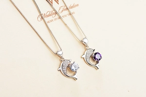 Detail of dolphin pendants in S999 silver with white and purple sparkling gemstones