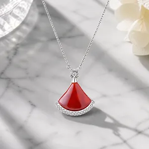 Macro shot of silver fan shaped necklace with red enamel pendant and tiny diamond
