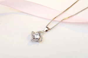 Close-up of S925 sterling silver four-leaf clover pendant with sparkling zircon on silk ribbon
