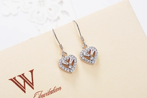 Macro shot of S925 sterling silver heart dangle earrings with zircon on a beige card