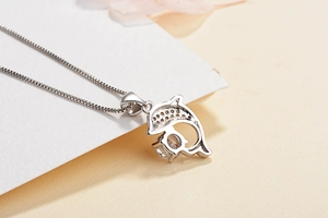 Macro shot of silver dolphin pendant featuring a large round zircon and fine box chain