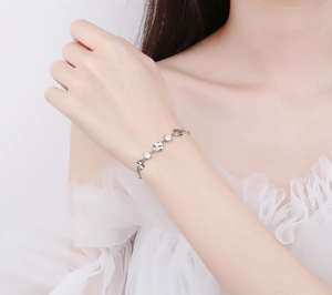 Elegante bracciale a quadrifoglio in argento indossato con un abito in pizzo bianco