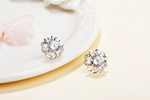 Macro shot of silver plum blossom stud earrings with zircon inlay and镂空petals