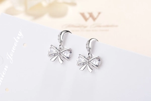 Macro shot of silver bow earrings with zircon stones showing detailed prong setting