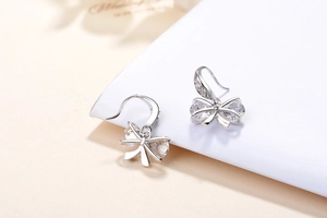 Macro shot of silver bow earrings with sparkling pear-cut and round cubic zirconia stones