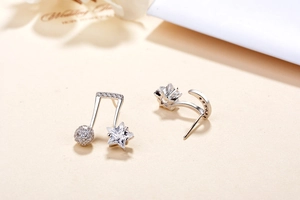 Macro shot of asymmetrical S925 silver earrings with music note, star and moon shapes