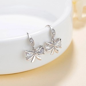 Elegant S925 sterling silver bow earrings with sparkling cubic zirconia on white ceramic