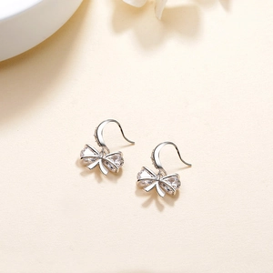 Elegant S925 sterling silver bow earrings with sparkling cubic zirconia on a textured surface