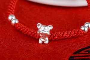 Macro shot of S999 silver zodiac tiger charm on handmade braided red cord bracelet