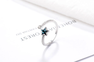 Macro detail of S925 silver ring with blue star and zircon pavé on white fabric