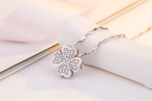 Macro shot of silver four-leaf clover pendant with sparkling pavé-set heart shaped petals