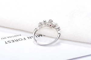 Macro detail of silver crown ring with white diamonds and a central red gemstone accent