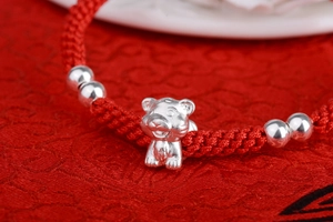 Macro view of S999 silver zodiac tiger charm on a hand-woven red braided rope bracelet