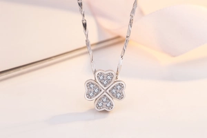 Macro shot of silver four-leaf clover pendant with pavé cubic zirconia on soft ribbon