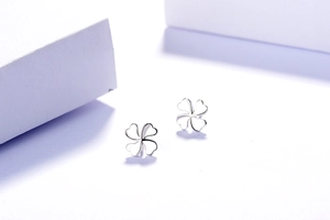 Vue détaillée des boucles d'oreilles trèfle en argent S925 sur décor minimaliste blanc