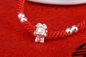 Macro shot of 999 sterling silver zodiac rabbit charm on handmade red woven bracelet
