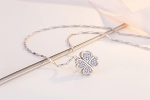 Detailed macro shot of silver four-leaf clover pendant with sparkling heart-shaped diamonds