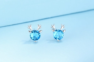 Detail of S925 sterling silver reindeer stud earrings with blue round-cut gemstones