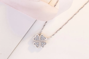 Macro detail of silver four-leaf clover pendant with pavé cubic zirconia heart petals