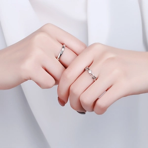 S925 sterling silver angel wing couple rings with diamonds shown on soft white fabric