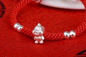 Macro shot of handcrafted red cord bracelet with silver Chinese zodiac animal charm