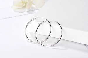 Détail de boucles d'oreilles créoles S925 en argent sur présentoir en cuir blanc