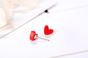Close-up of S925 sterling silver heart earrings with glossy red finish on white background